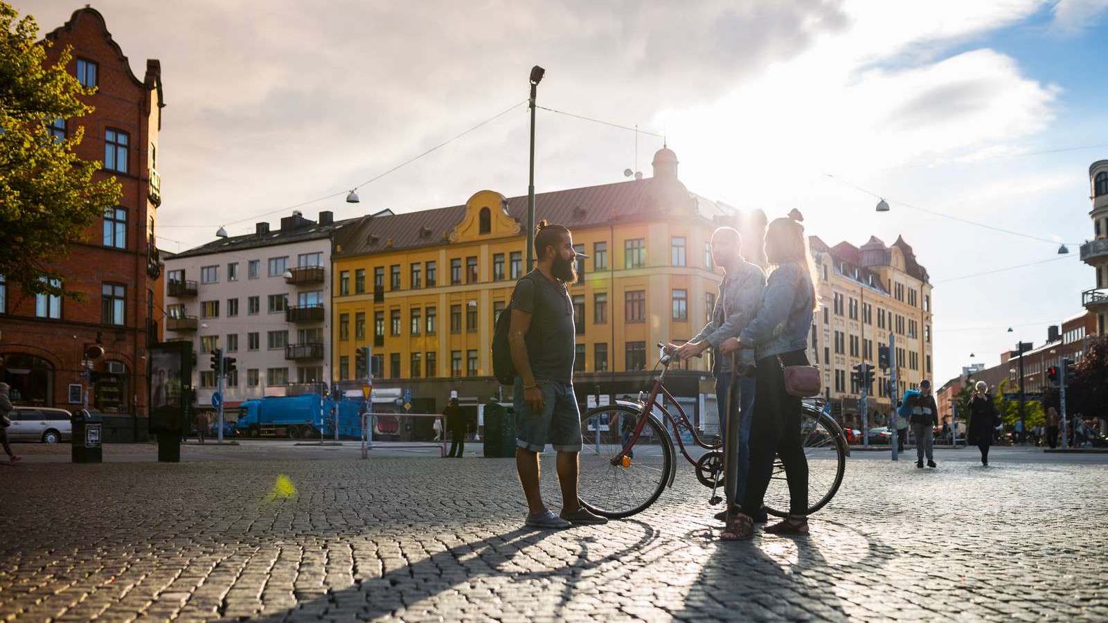 Tre mennesker står sammen på en plads i en by