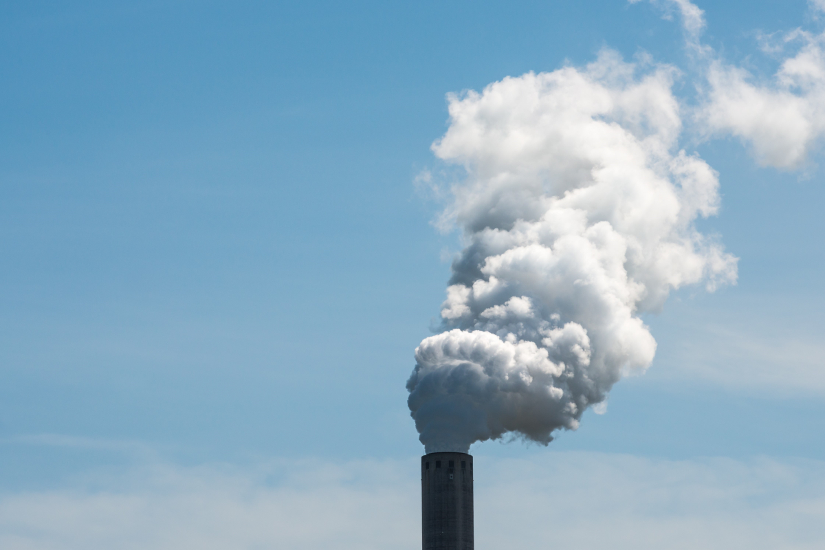 Industriel skårsten der ryger på blå himmel