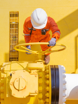 En mand med en sikkerhedshjelm drejer på en ventil