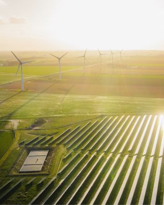 Grøn mark med solceller og vindmøller på land